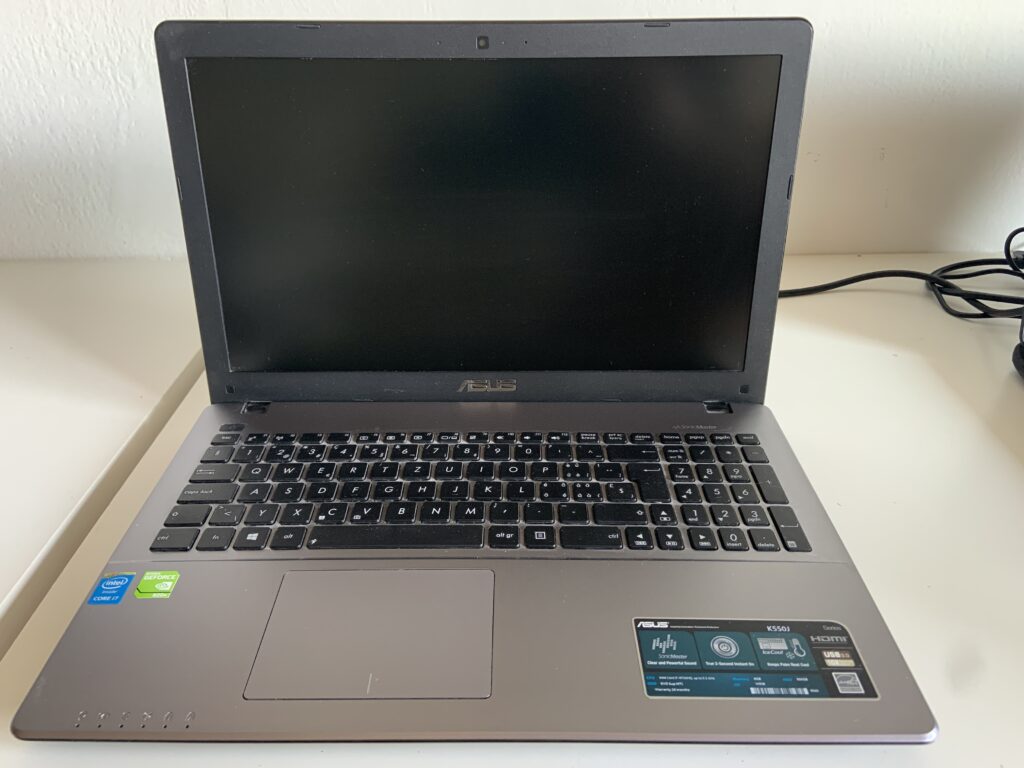 ASUS K550J aperto sul banco per la sostituzione del trackpad, riparazione per un cliente di Cugnasco